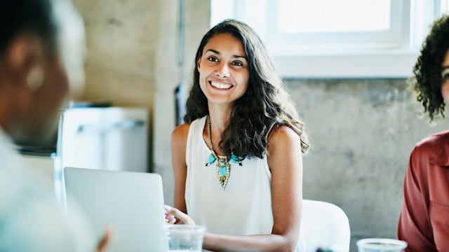 Smiling businesswoman in discussion with colleagues during meeting in office conference room