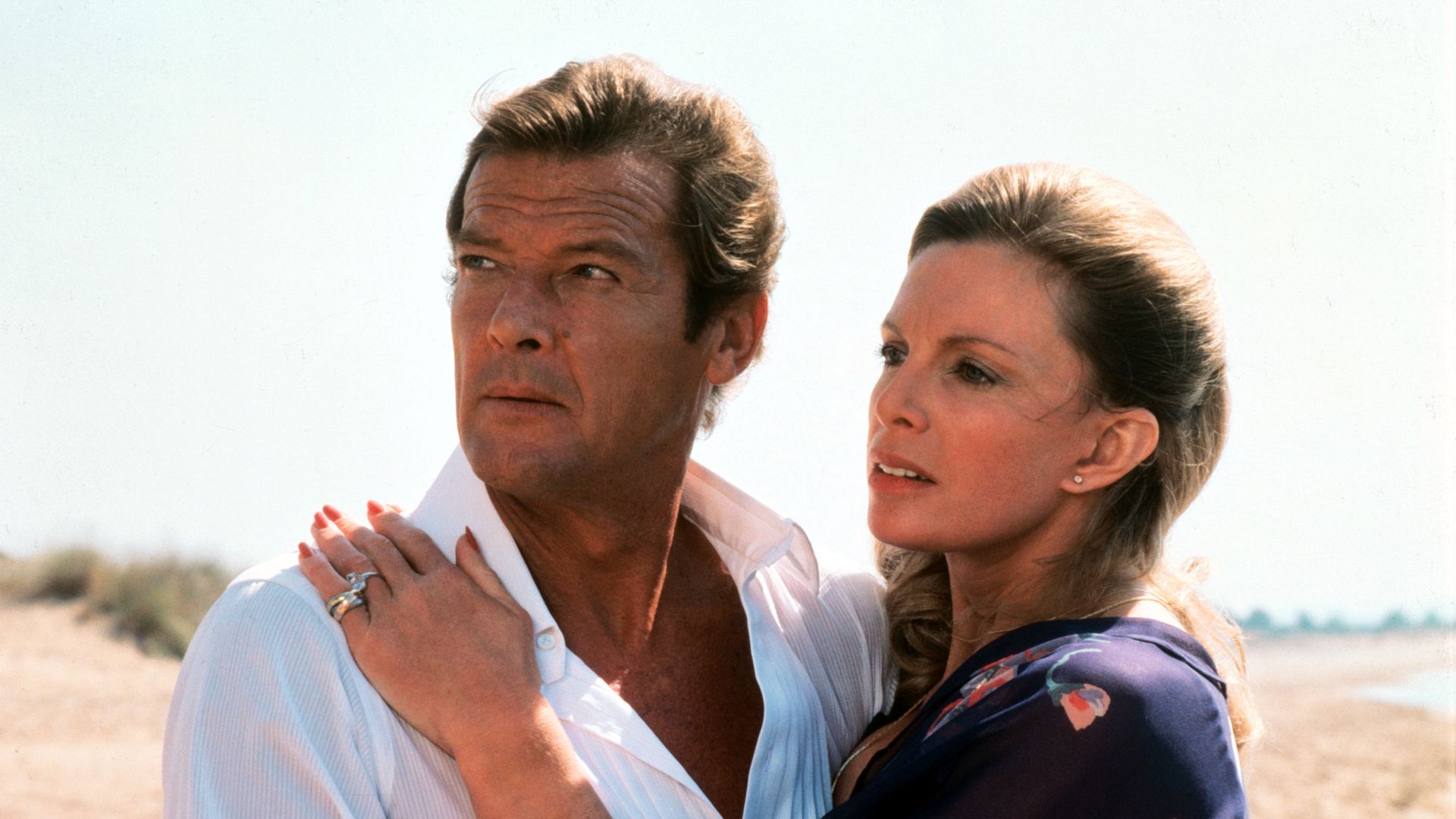 Still image of Roger Moore and Cassandra Harris embracing on a beach in For Your Eyes Only