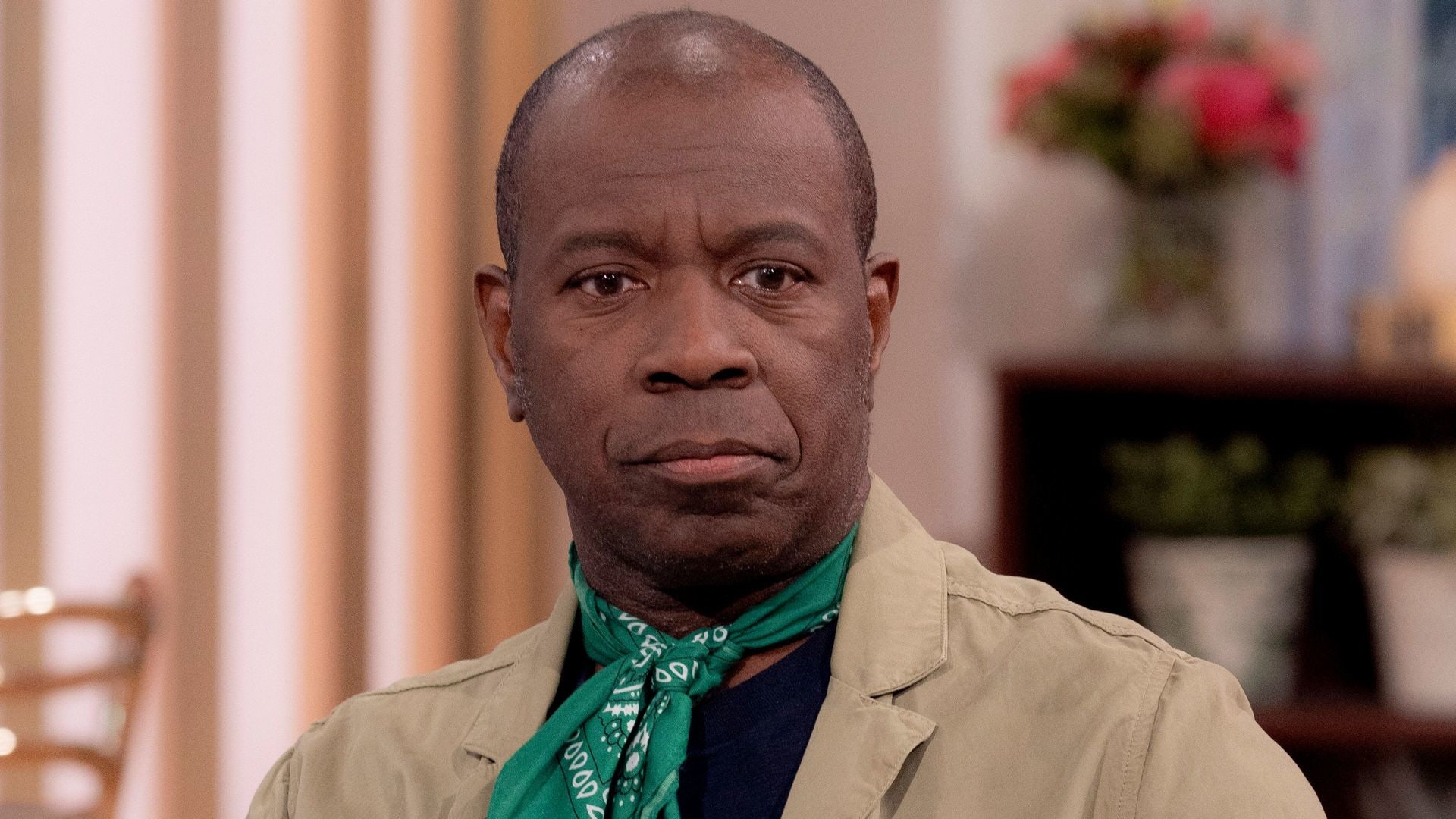 Clive Myrie wearing khaki jacket and green neckerchief while sitting on the This Morning sofa