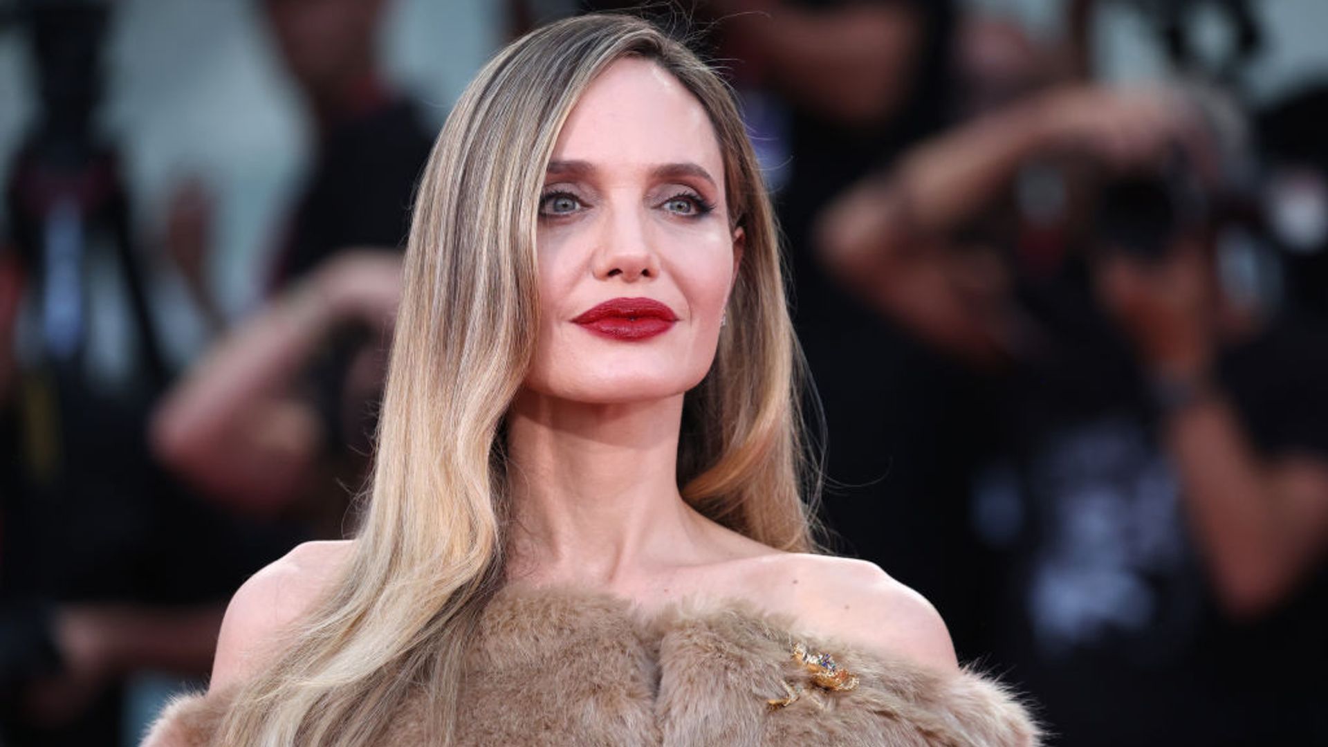 angelina jolie with blonde hair and a red matte lip