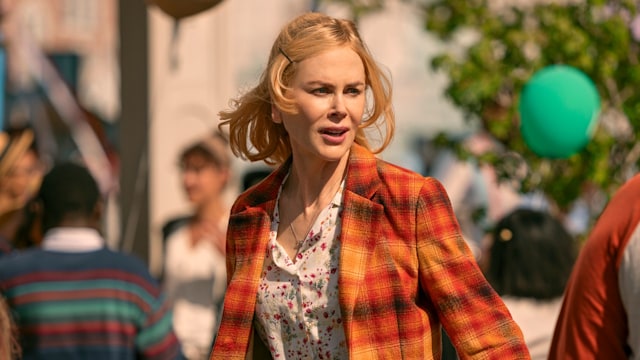 Close-up of blonde woman in orange jacket in busy street