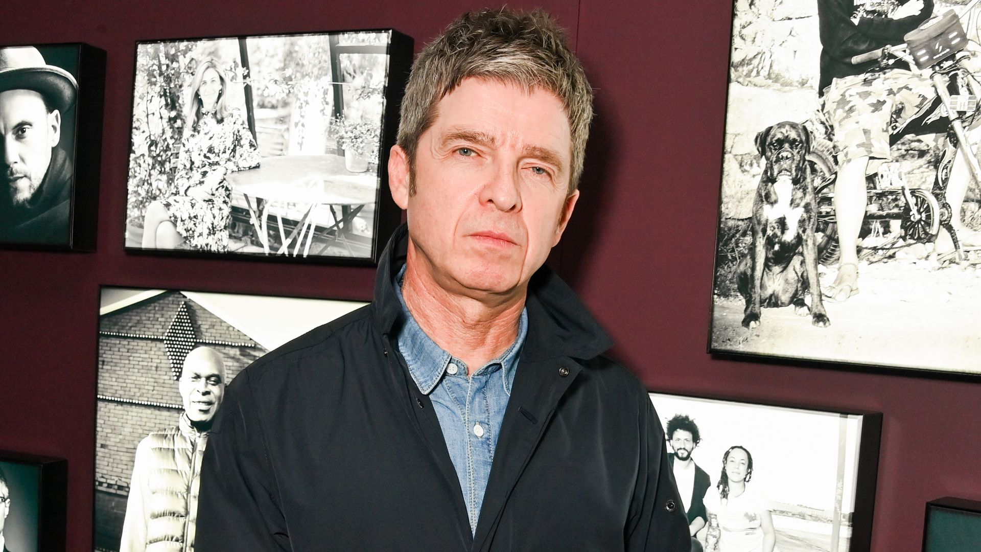 Noel Gallagher standing in front of wall of art at National Portrait Gallery 