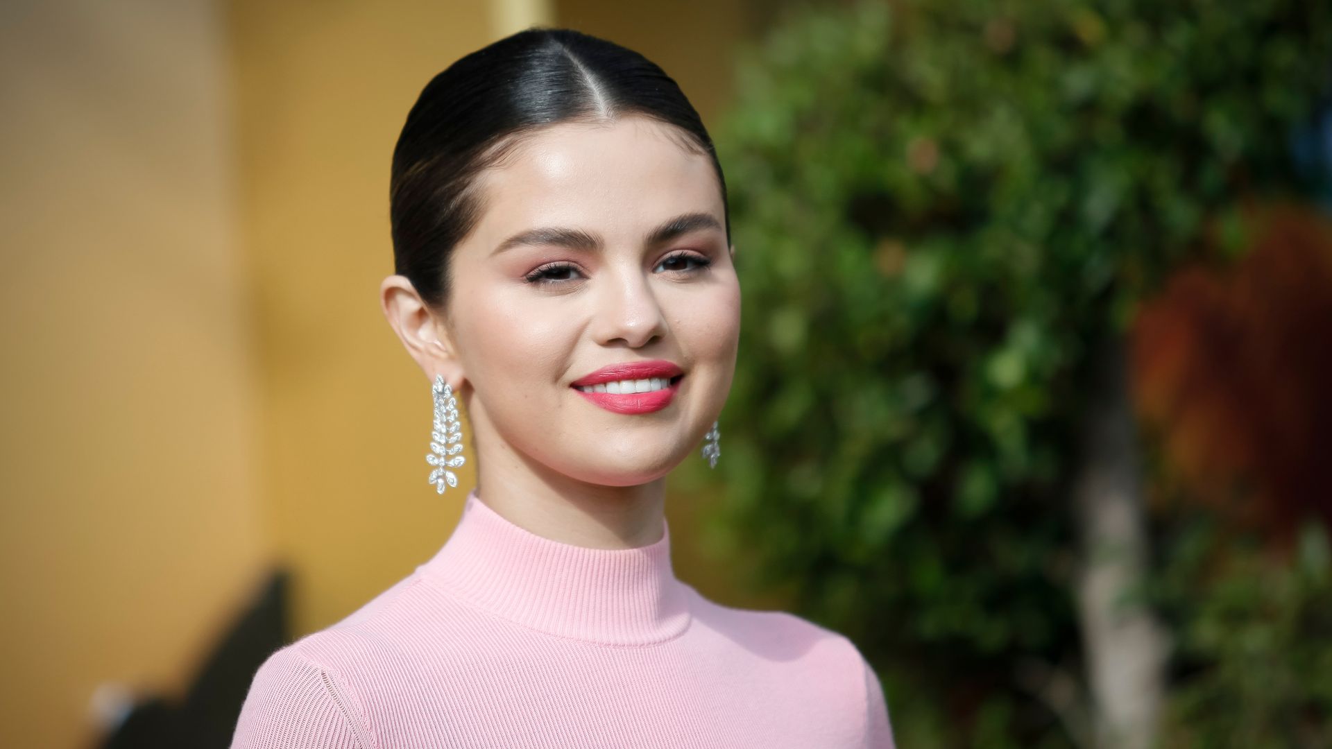 Selena Gomez wearing a pink high neck top and dazzling earrings 