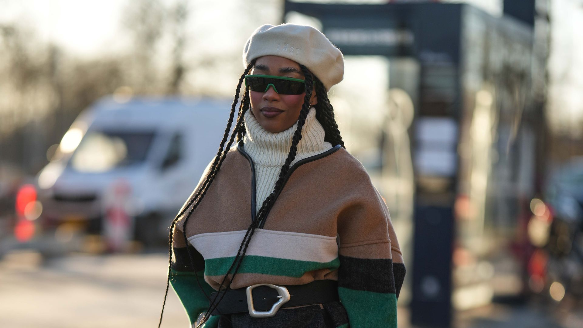 Woman wearing white wool felt beret hat from Last, green sunglasses, a white ribbed wool turtleneck pullover with fringing