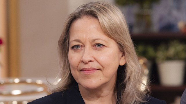 woman in black blazer sitting on sofa in tv studio
