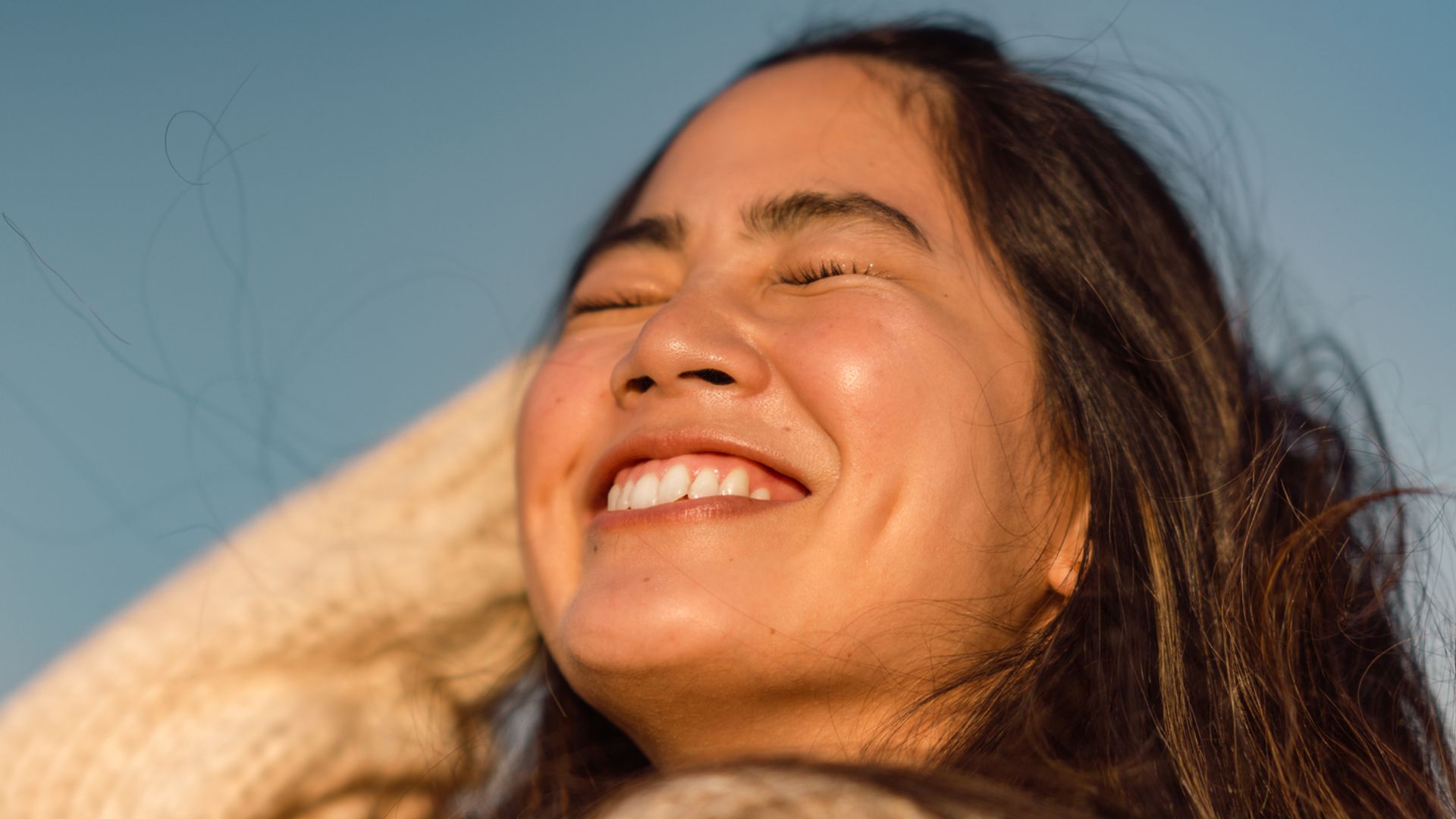 A portrait of a beautiful woman at the beach during sunset.