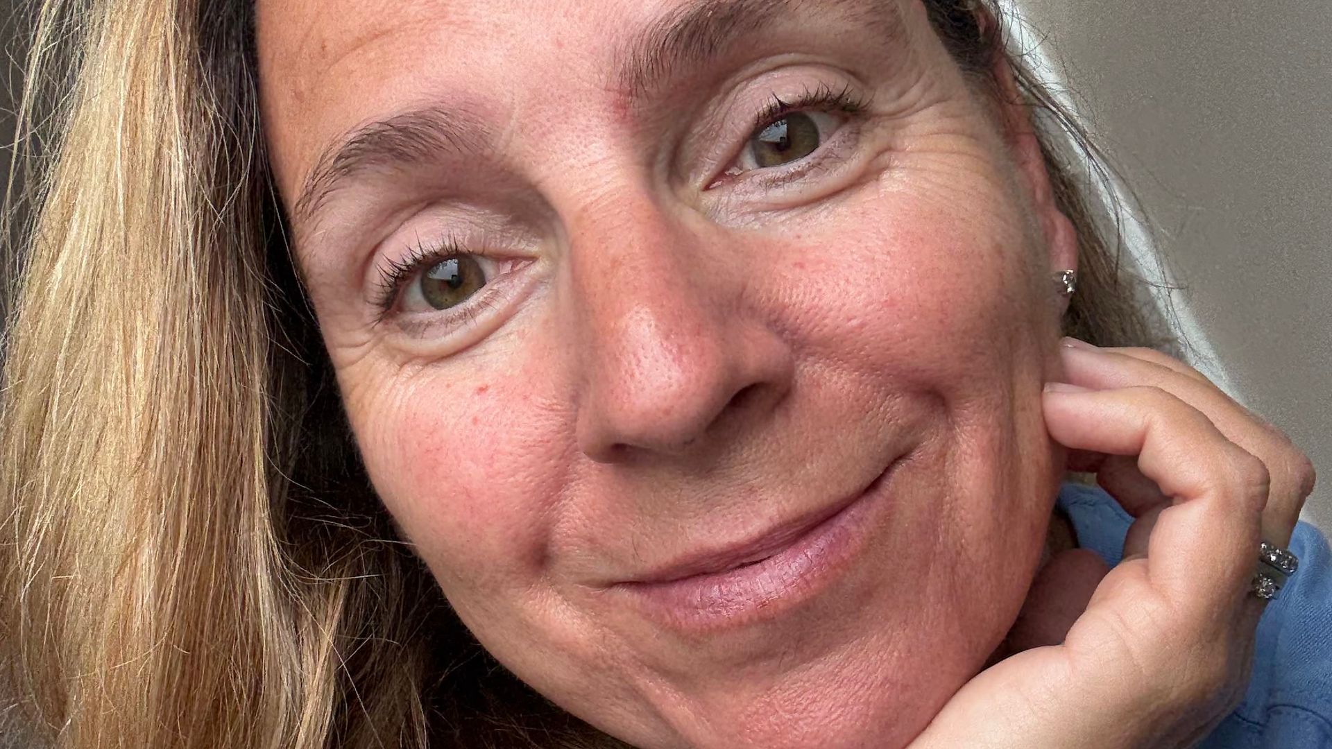 woman with no makeup on smiling for a selfie 