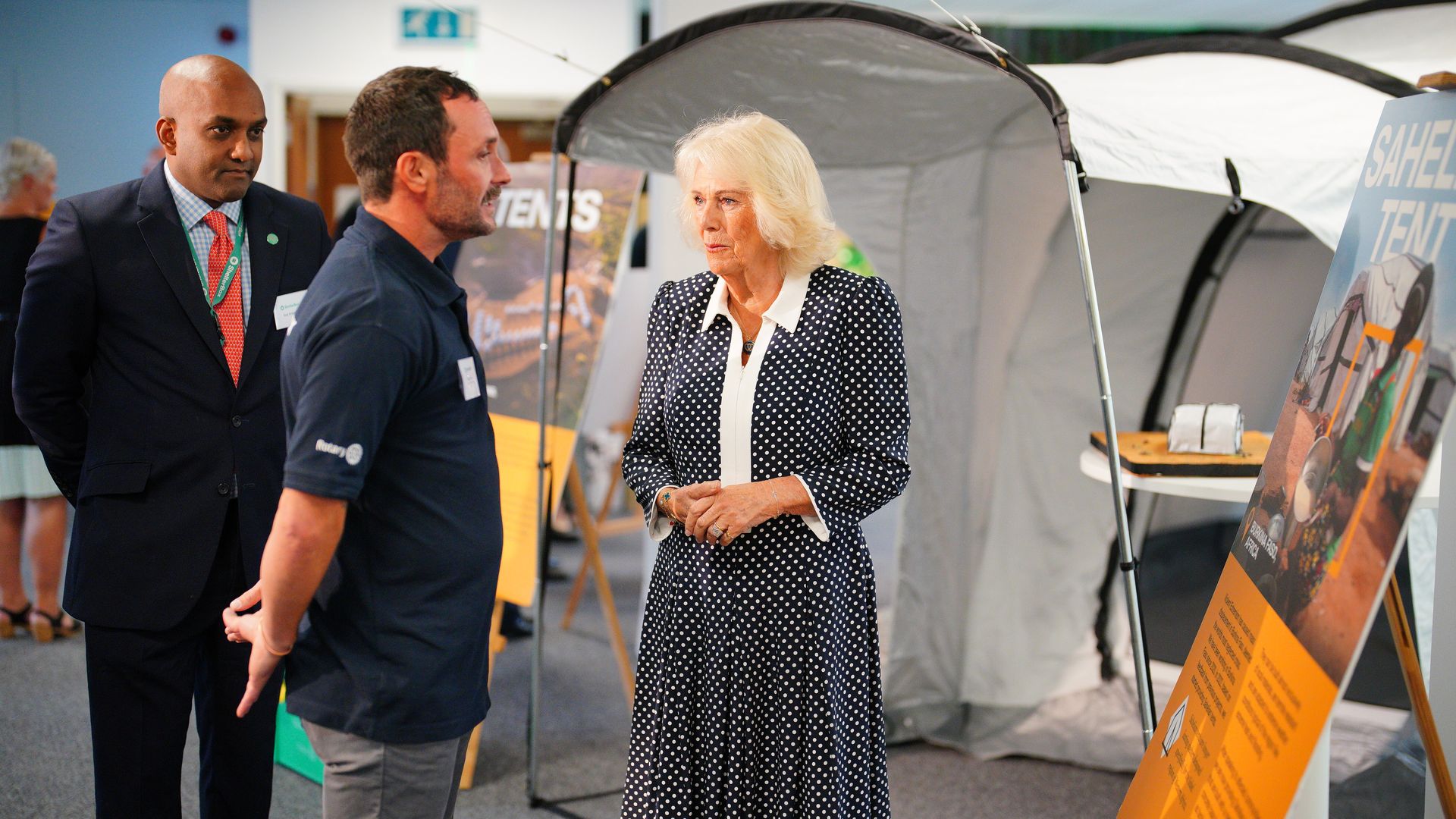 Queen Camilla touring a facility standing by some tents
