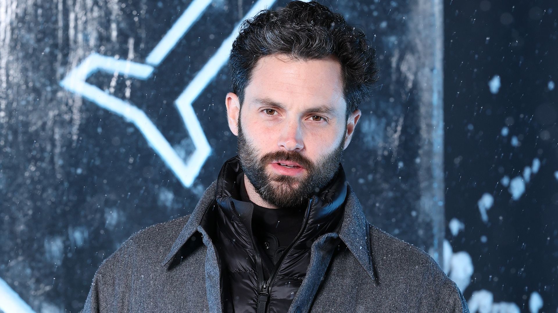 penn badgley wearing a coat in front of ice sculpture