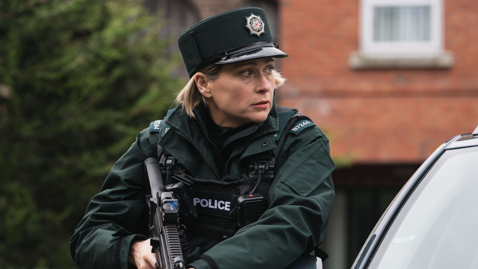 police officer holding gun next to car