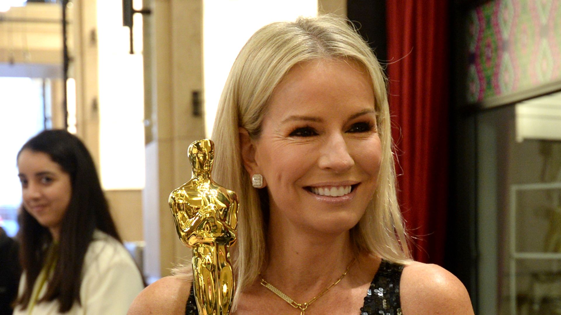 Jennifer Ashton holding an Oscar in a black dress