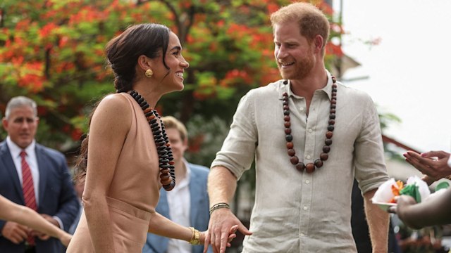 Harry and Meghan hold hands as they arrive at school in Nigeria