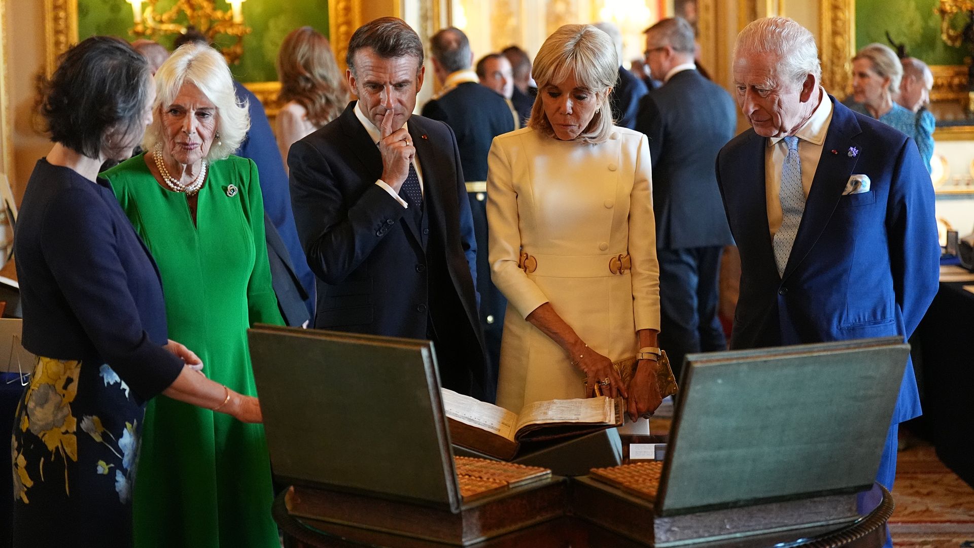 Queen Camilla, Emmanuel Macron, Brigitte Macron and King Charles looking at items in the royal collection