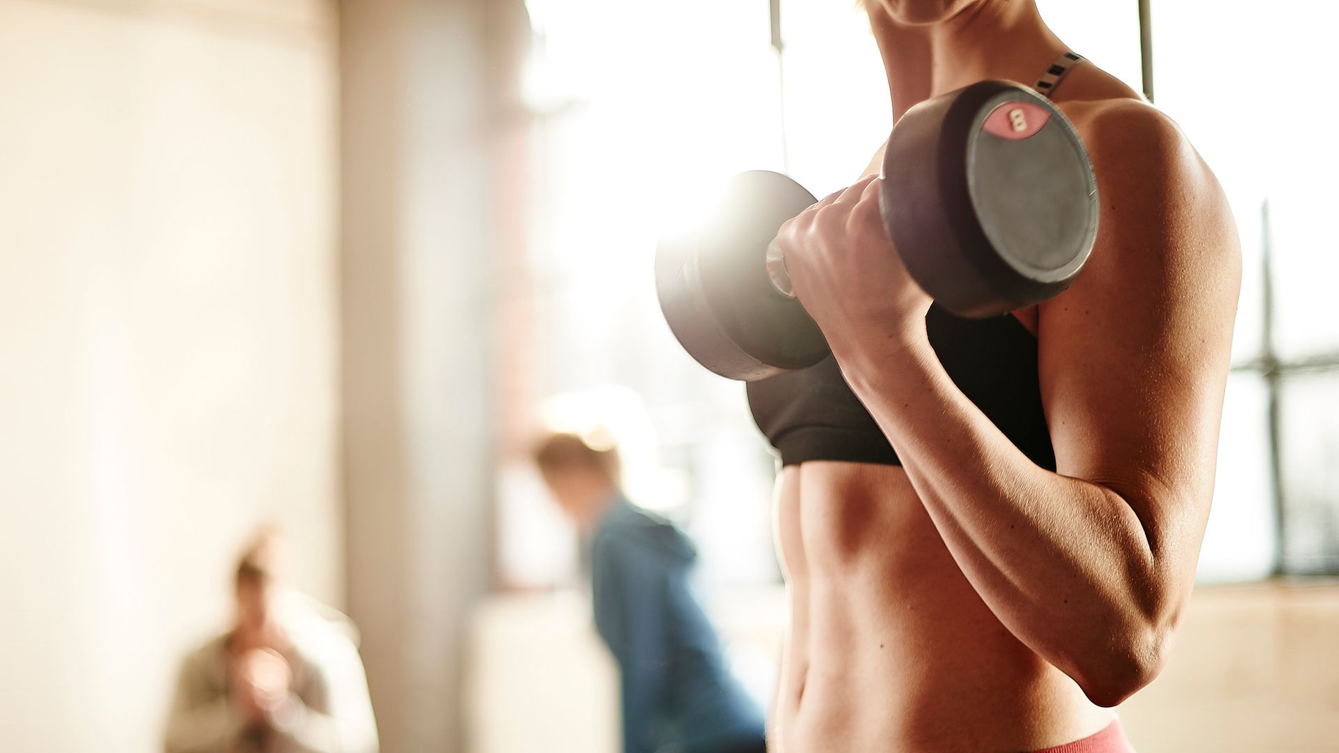 Healthy young female weight training in gym.