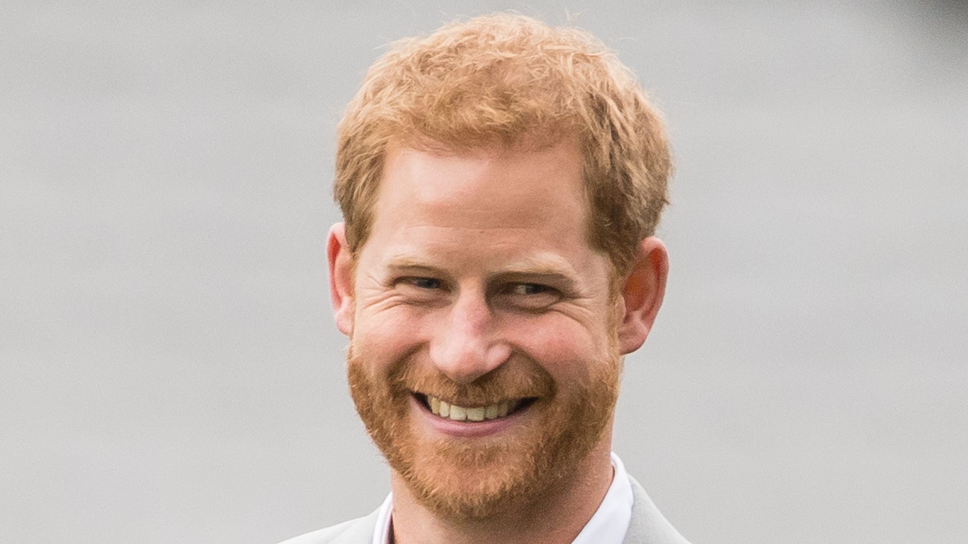 Prince Harry smiling in grey suit 