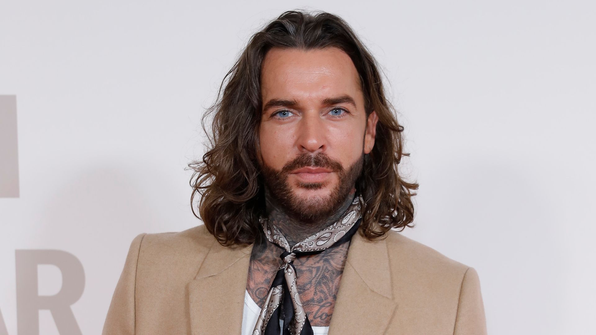 Pete Wicks poses in camel blazer