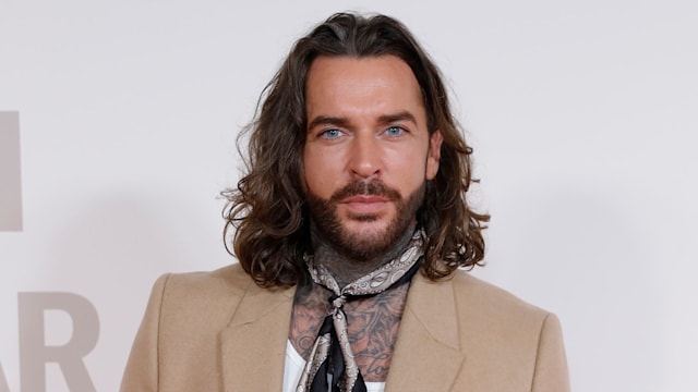 Pete Wicks poses in camel blazer