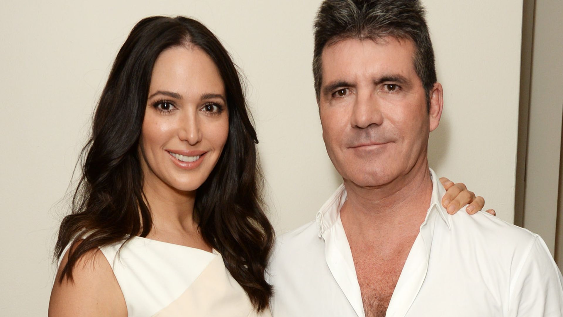 Lauren Silverman in a white midi dress next to Simon Cowell in an open white shirt