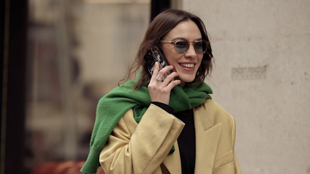 Alexa Chung wears blue jeans, beige coat and green sweater over the shoulders outside The Row during the Womenswear Fall/Winter 2024/2025 as part of  Paris Fashion Week on February 28, 2024 in Paris, France.