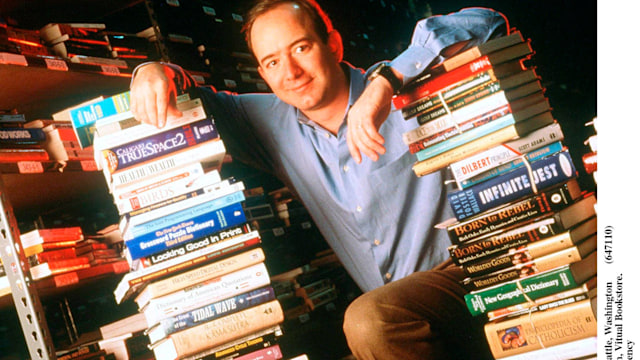 Jeff Bezos, founder & CEO of Amazon.com, poses with a stack of books in an Amazon warehouse, Seattle, Washington, January 1st 1997