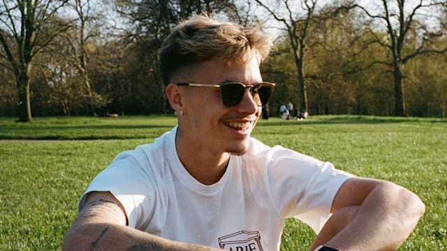 Romeo Beckham smiles on grass