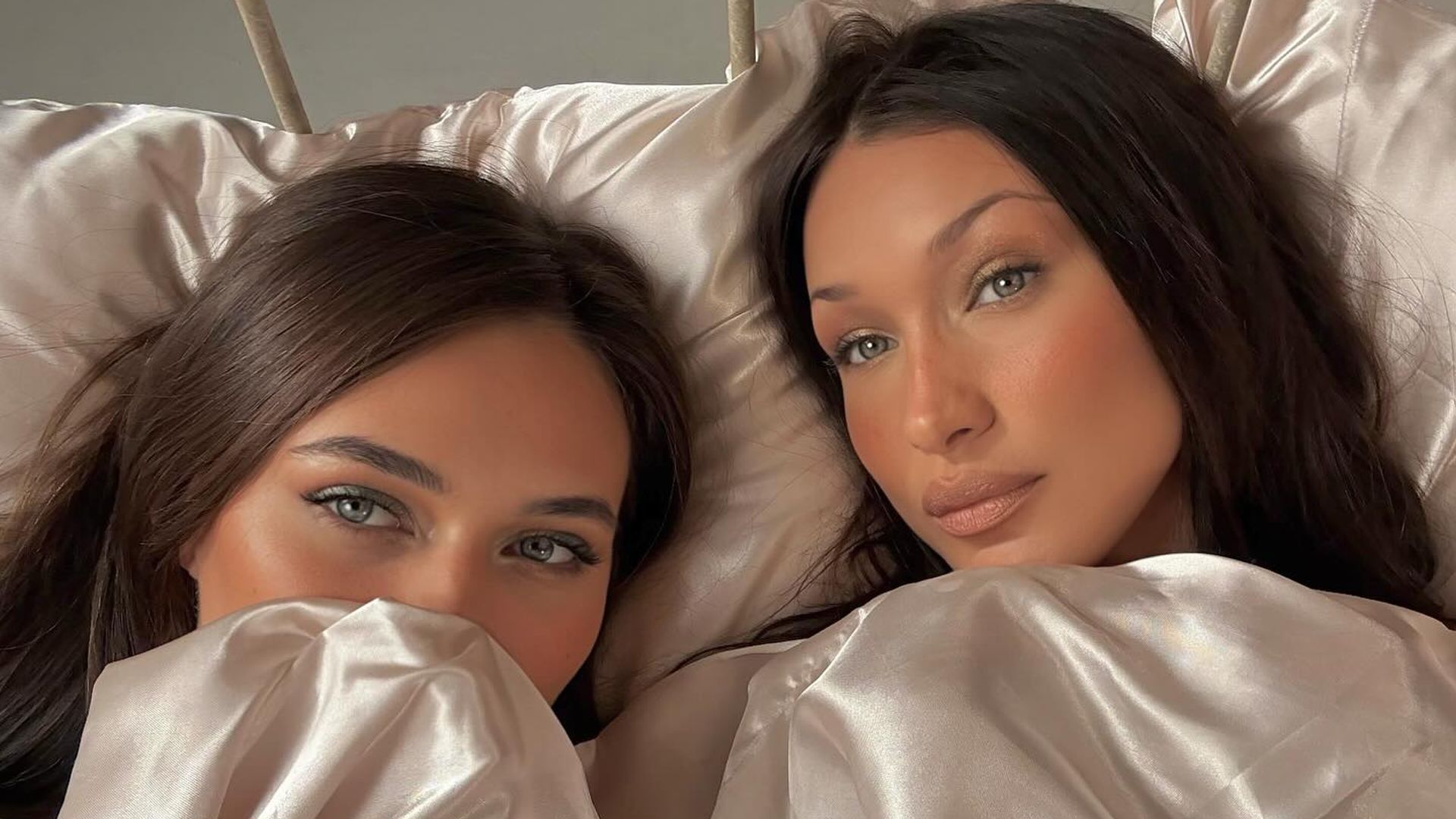 Bella Hadid and Devon Carlson pose for a picture on a bed