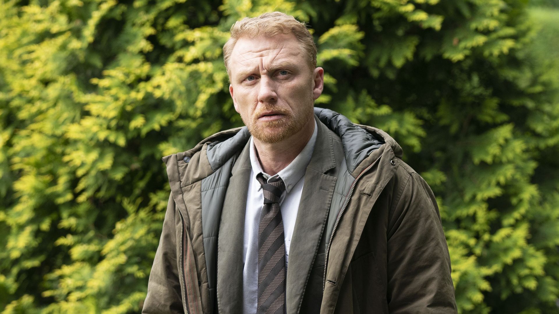 Kevin McKidd in front of a bush in Six Four