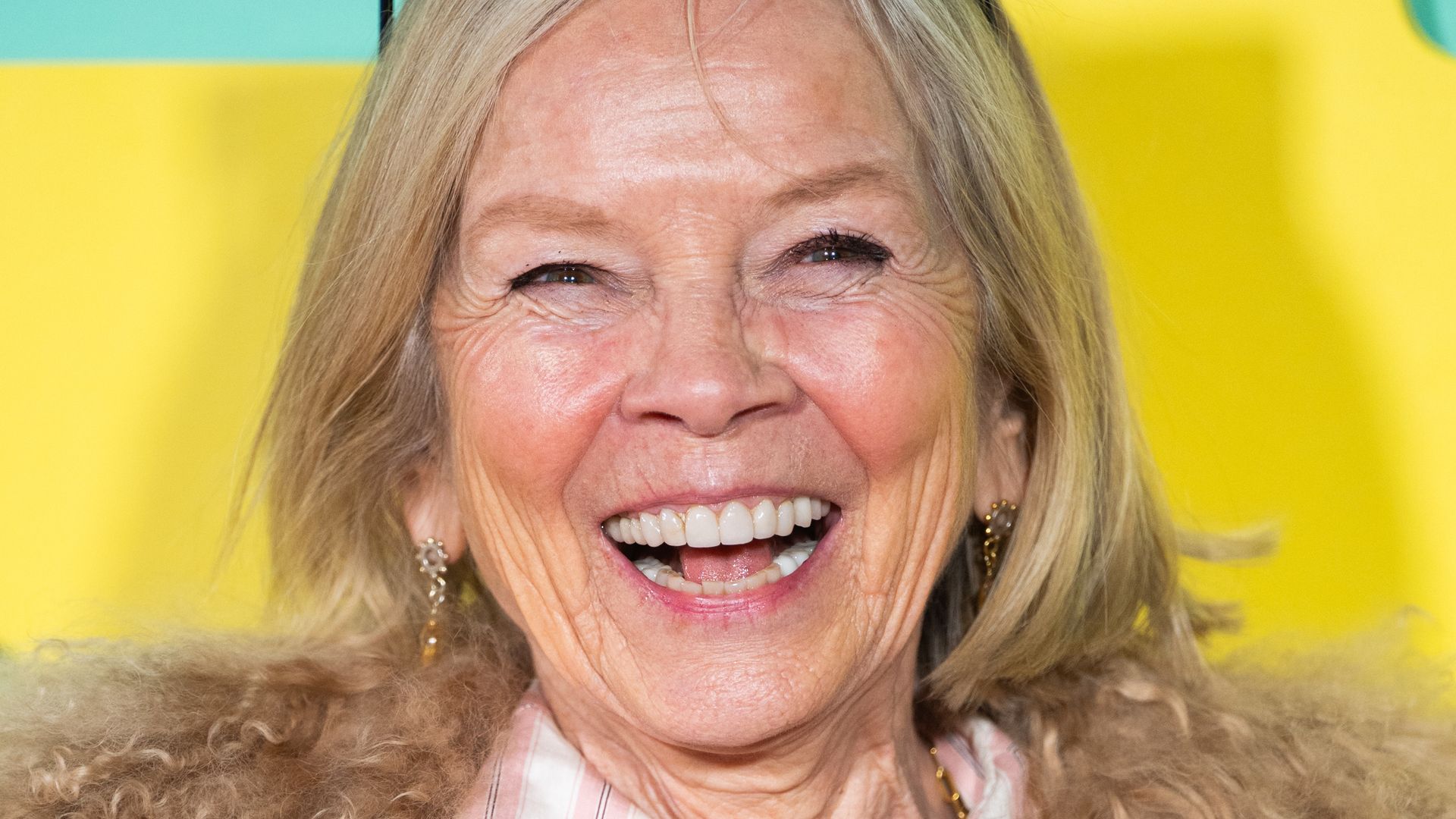 Jo Wood in a fluffy coat and striped blouse smiling widely