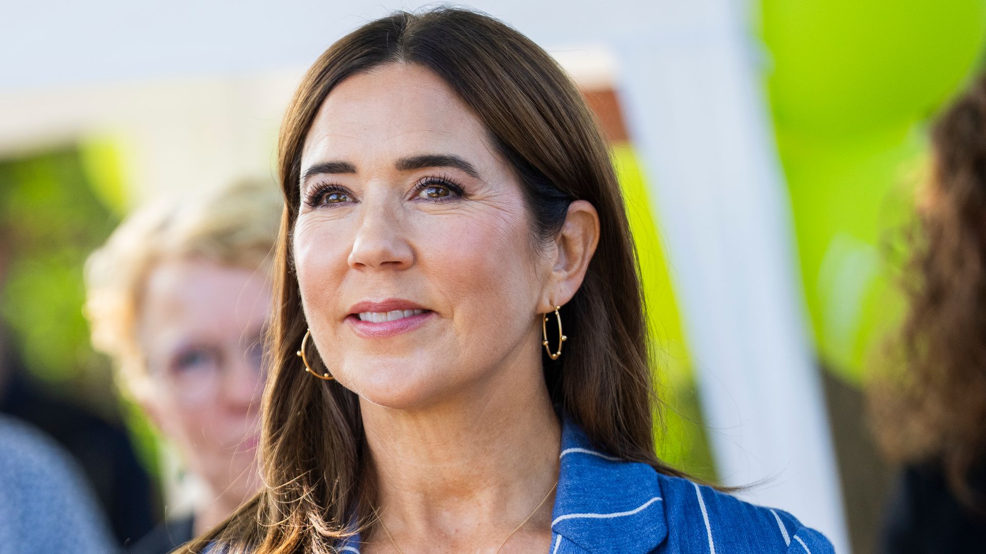 Queen Mary in blue pinstriped suit and gold earrings/necklace 