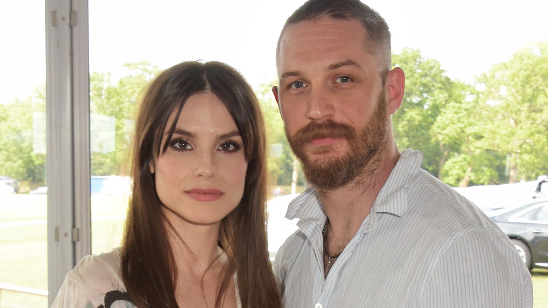 Charlotte Riley looking straight-faced in a white dress with Tom Hardy