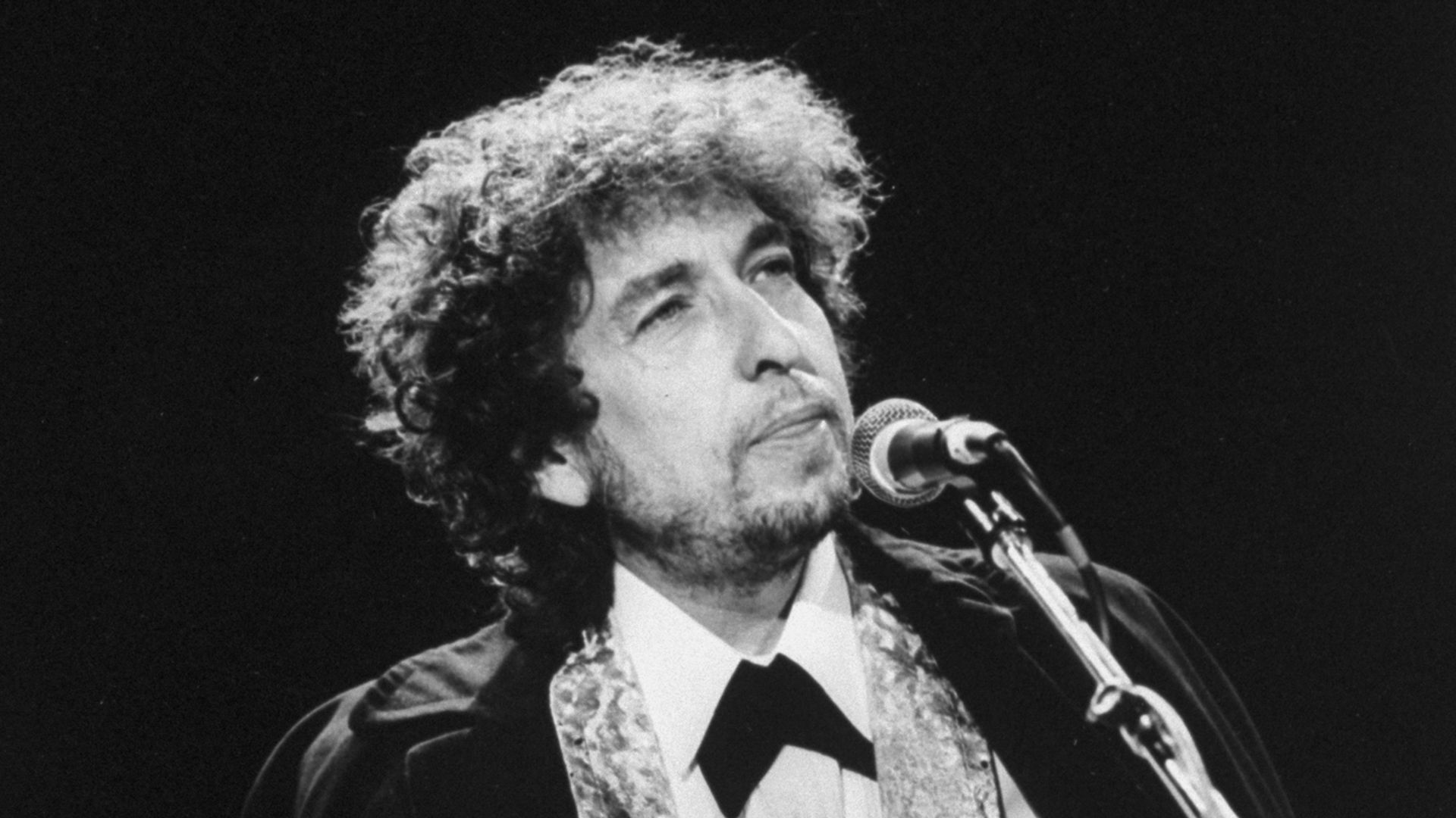 Black-and-white photo of Bob Dylan in front of a microphone
