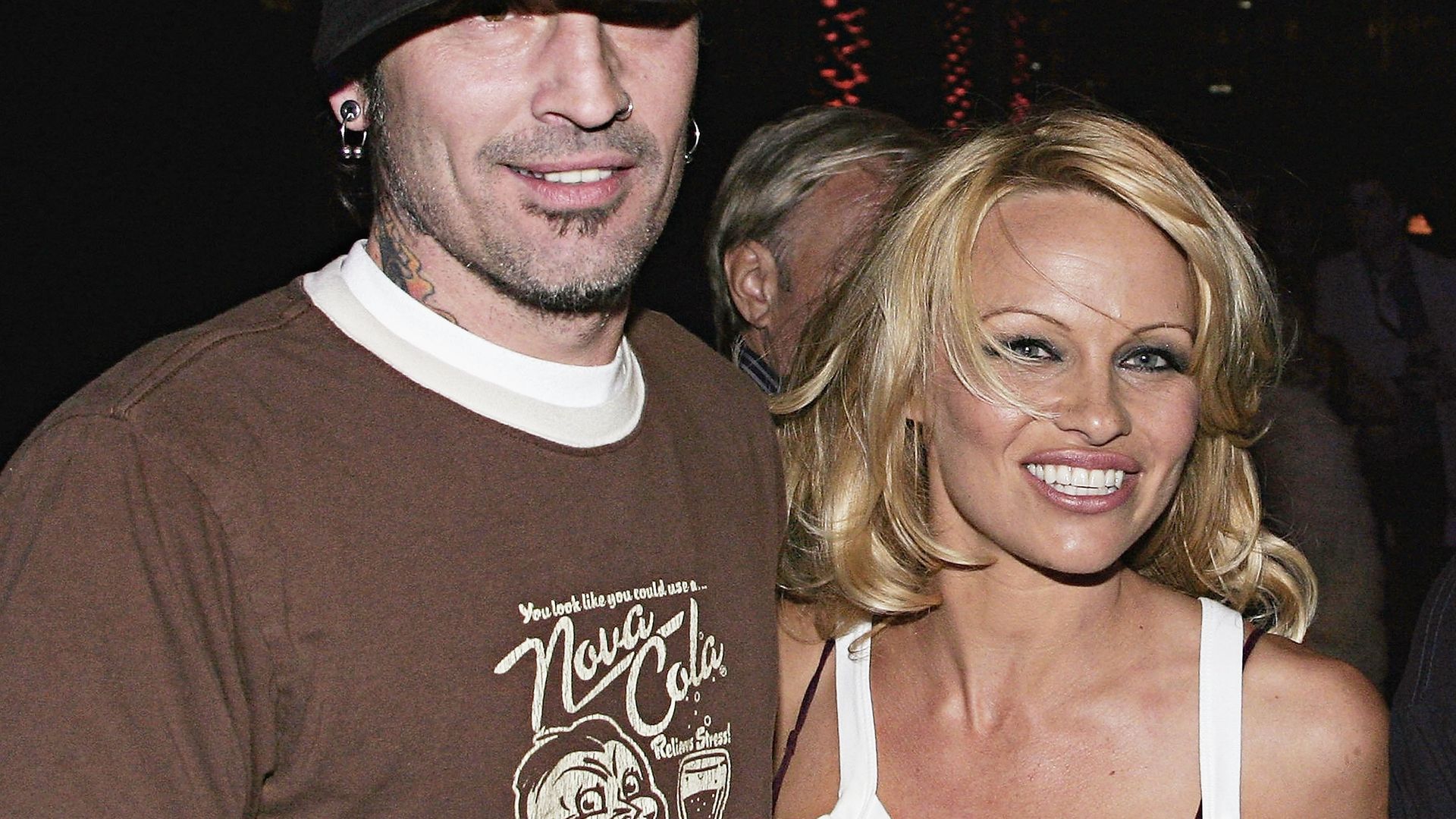 Pamela wearing a white vest top and tommy wearing a brown t-shirt and black hat 