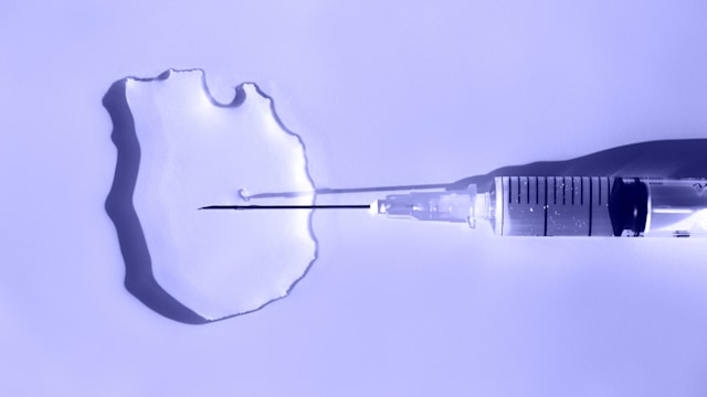 Sterile syringe with thin needle injects a liquid drug into a puddle on violet background. Macro photography in flat lay style with copy space. Demonstrating very peri - color of 2022 year