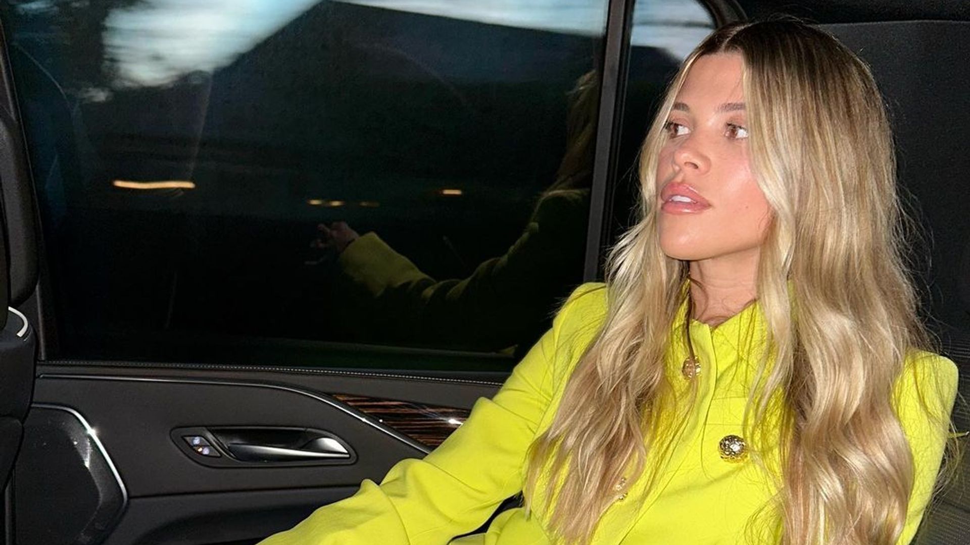 Sofia Richie wears a yellow blazer in the back of a car
