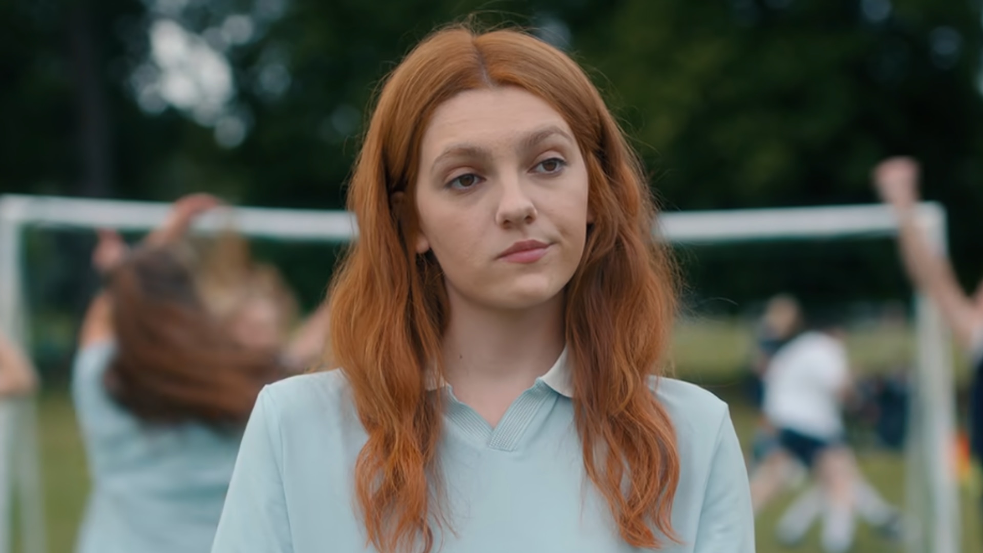 teenage girl with red hair standing on football pitch