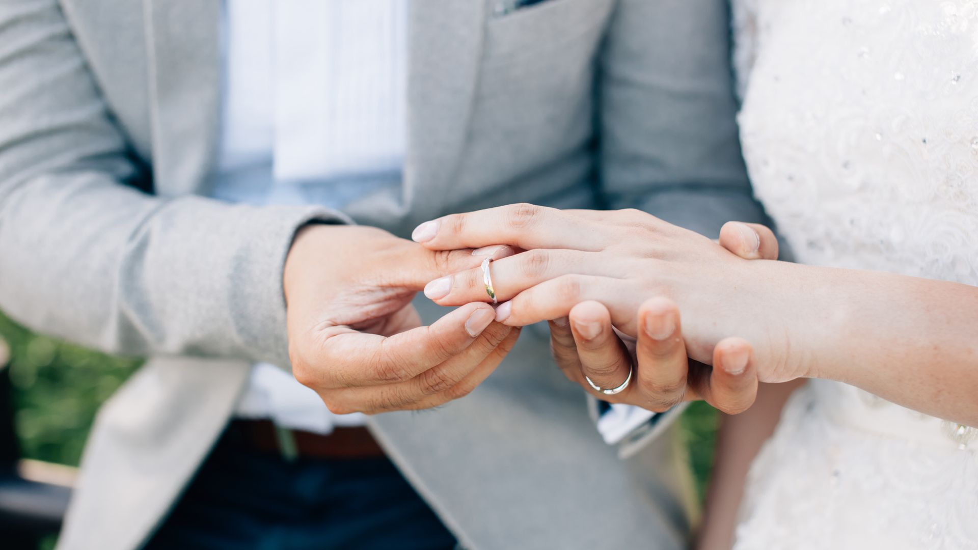 Groom putting ring on finger of bride