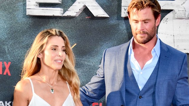 Elsa Pataky in a white dress next looking away from Chris Hemsworth
