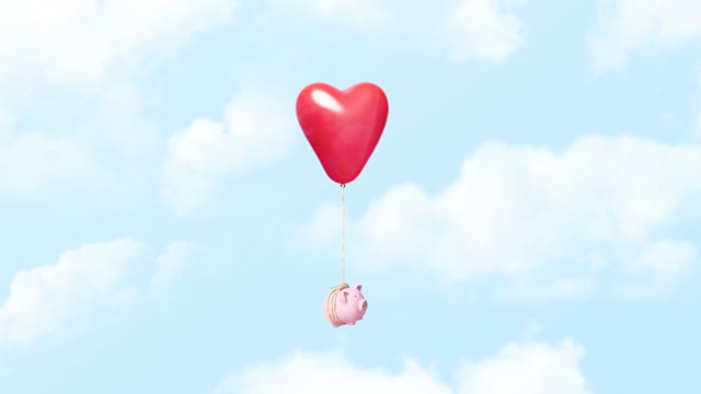 Horizontal conceptual image of a single pink piggy bank tied to a red heart balloon with a rope floating through the clouds, could illustrate concepts like couple and relationship finances, dating costs, moving away from home, or even opposite things like loosing ones savings in a divorce or breakup