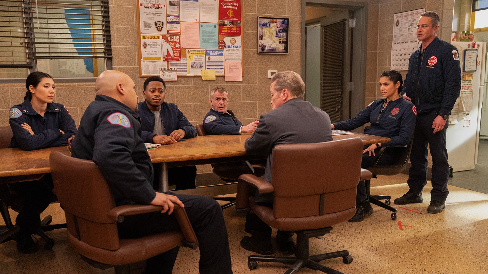 Chicago Fire cast sitting around a table looking somber
