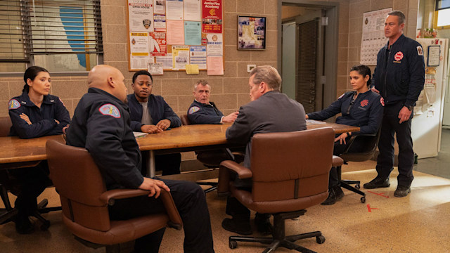 Chicago Fire cast sitting around a table looking somber 