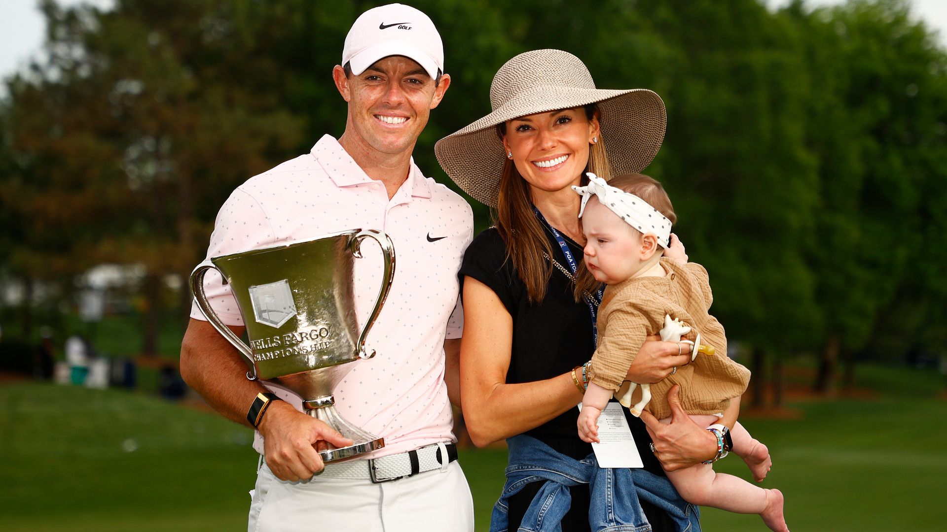 Rory McIlroy with his wife Erica and daughter Poppy smiling with a trophy