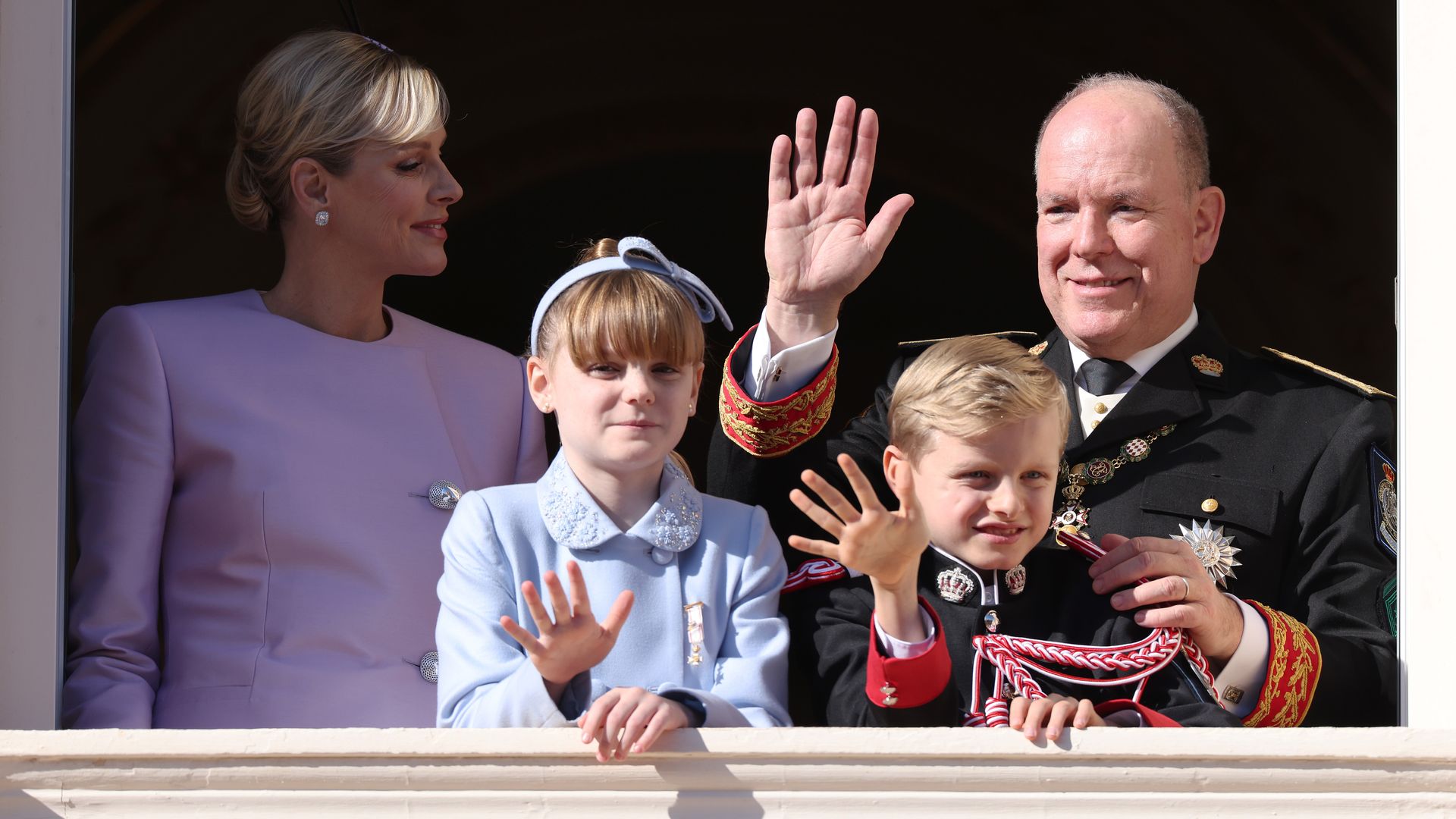 family of four waving on palace balacony