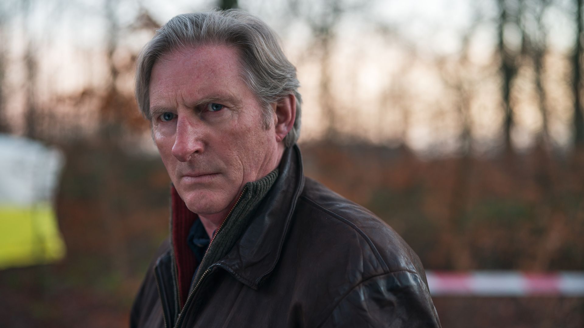 CLOSE-UP OF MAN IN LEATHER JACKET IN WOODS