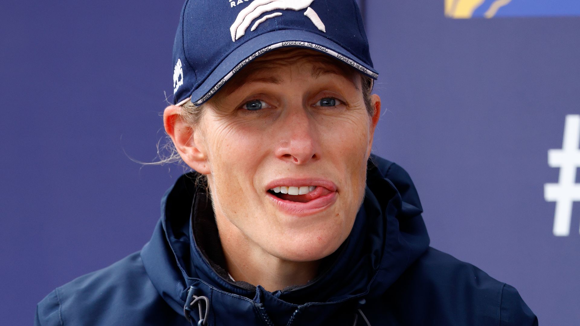 Zara Tindall in cap with her hands clasped between her legs