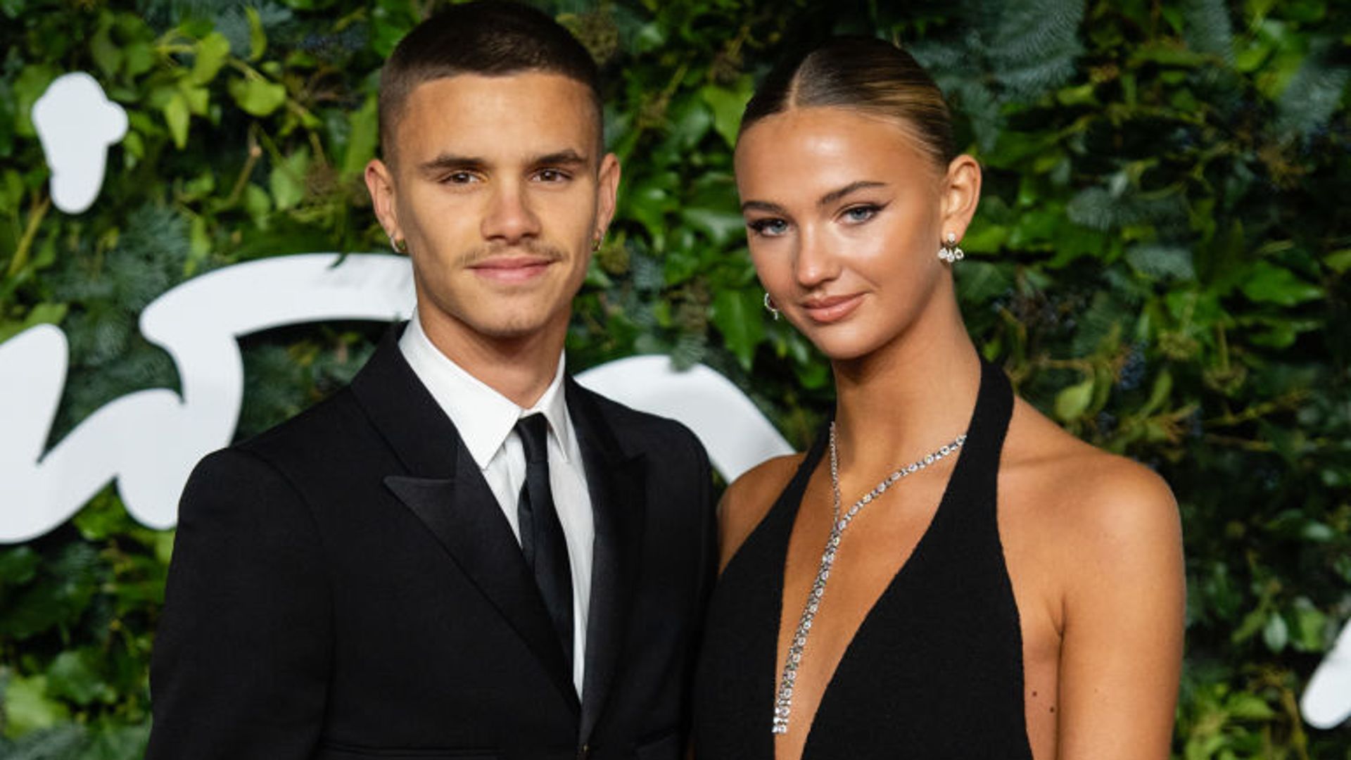 Mia Regan and Romeo Beckham in a black suit and black dress 