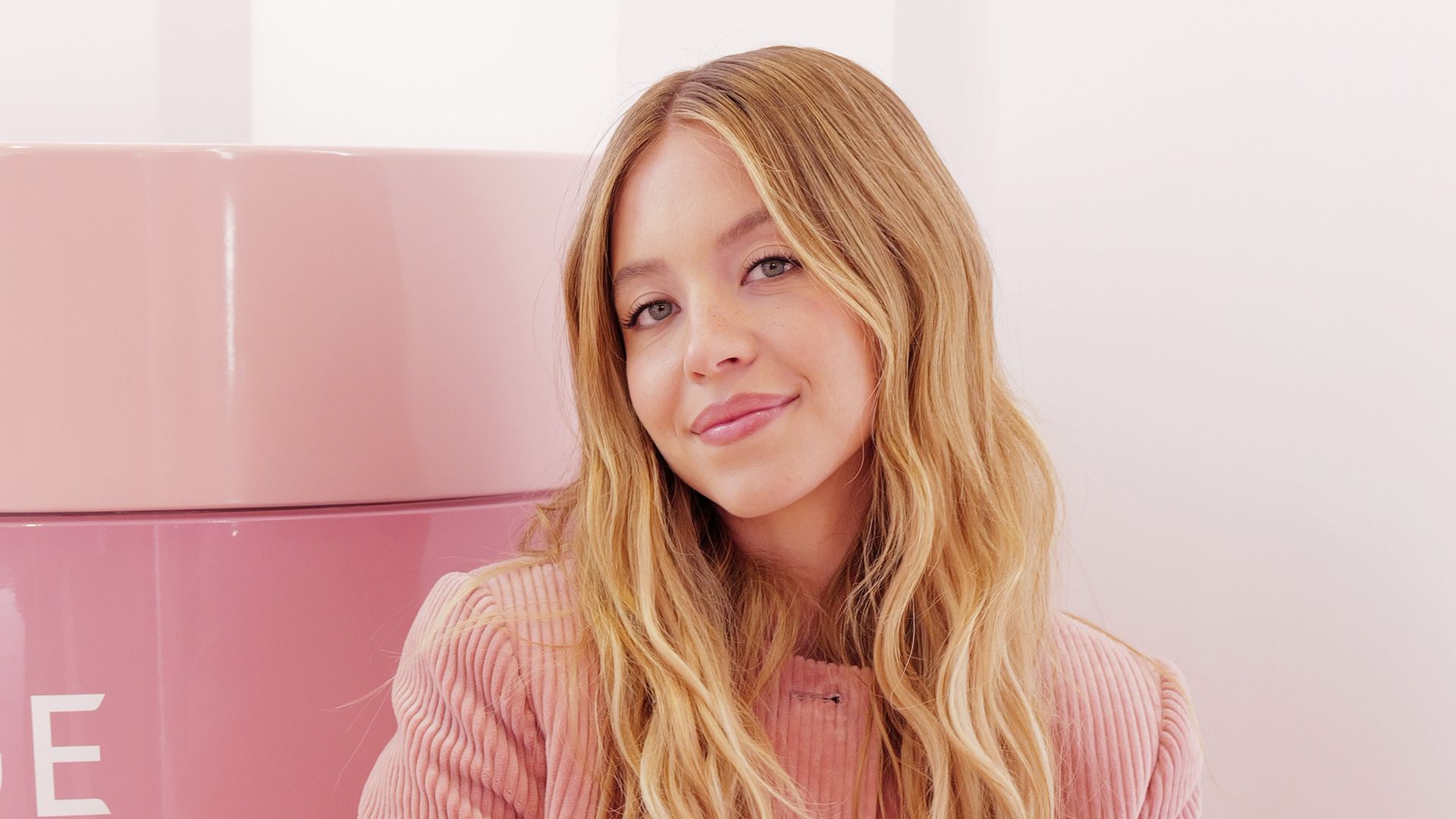 Sydney Sweeney and LANEIGE celebrate the launch of Bouncy & Firm Serum at La La Land Kind Cafe on April 02, 2025 in Los Angeles, California wearing a pink velvet jacket and blue jeans