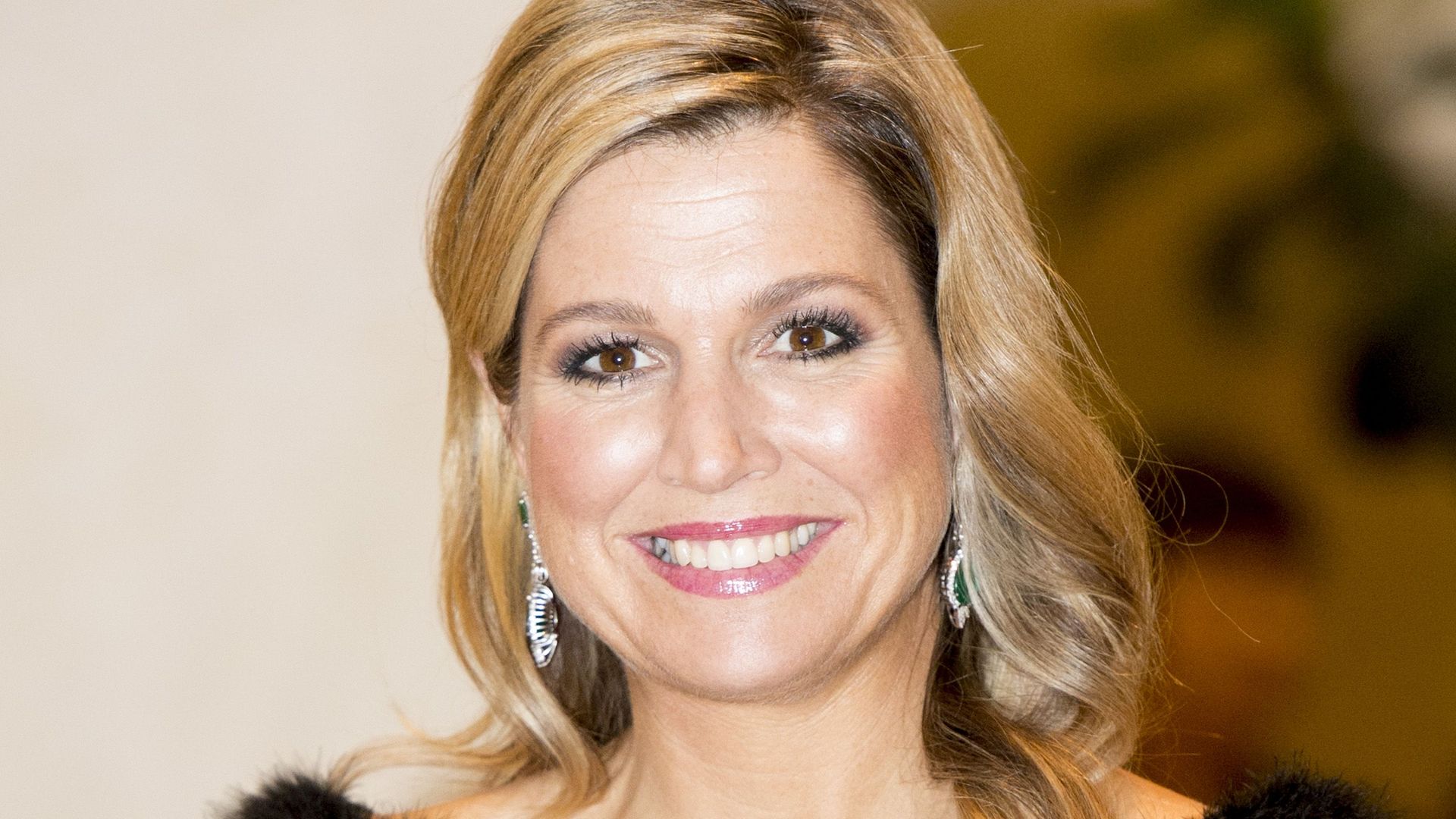 Queen Maxima smiling in a feathered black dress