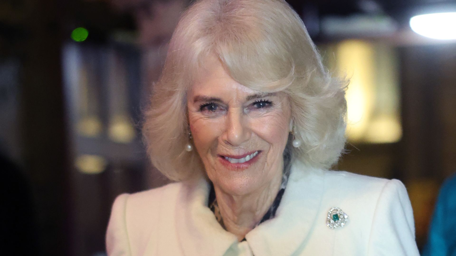 Queen Camilla in a white coat with flowers in her hand