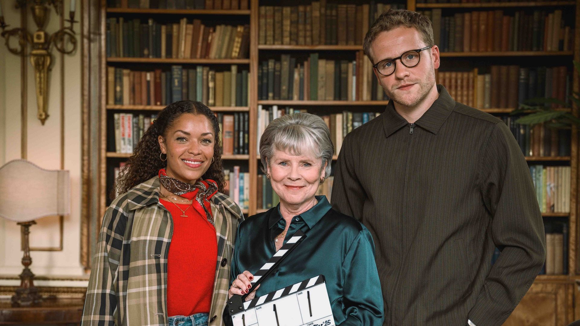 three actors standing in office library holding clapperboard