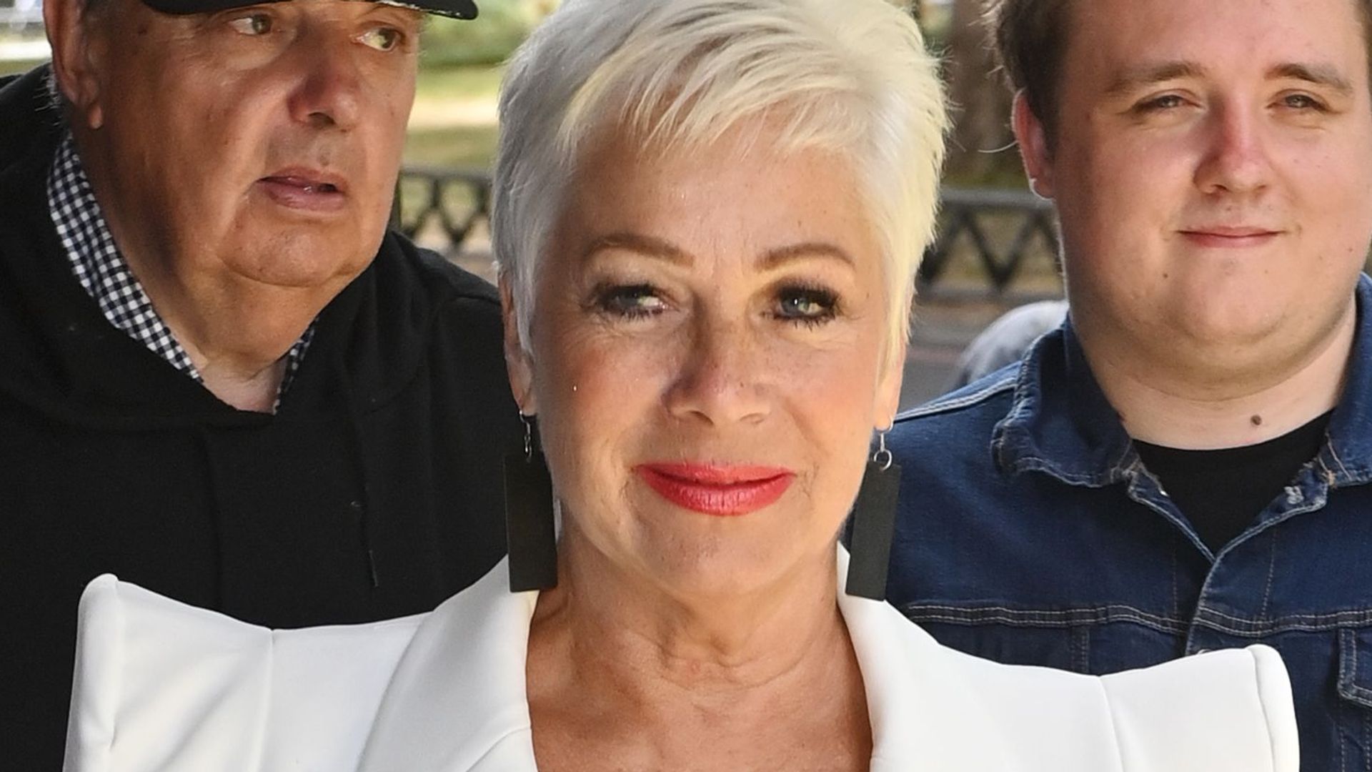 Denise Welch in a white suit with red lipstick on the red carpet
